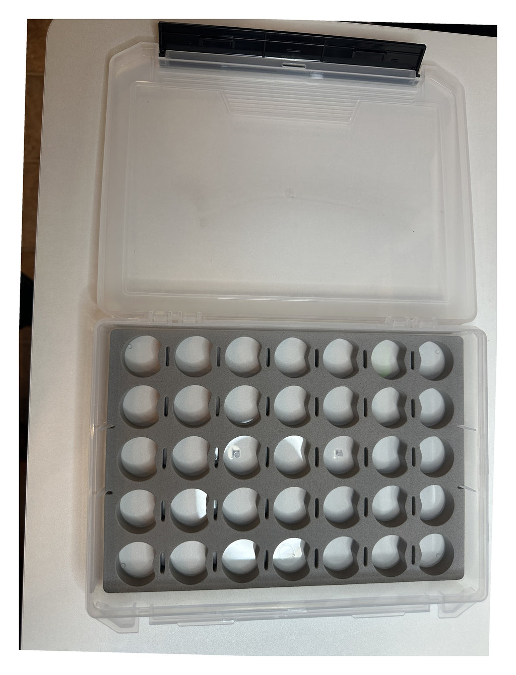 Thread storage box open - clear lid beside the gray foam insert with 35 spool holes