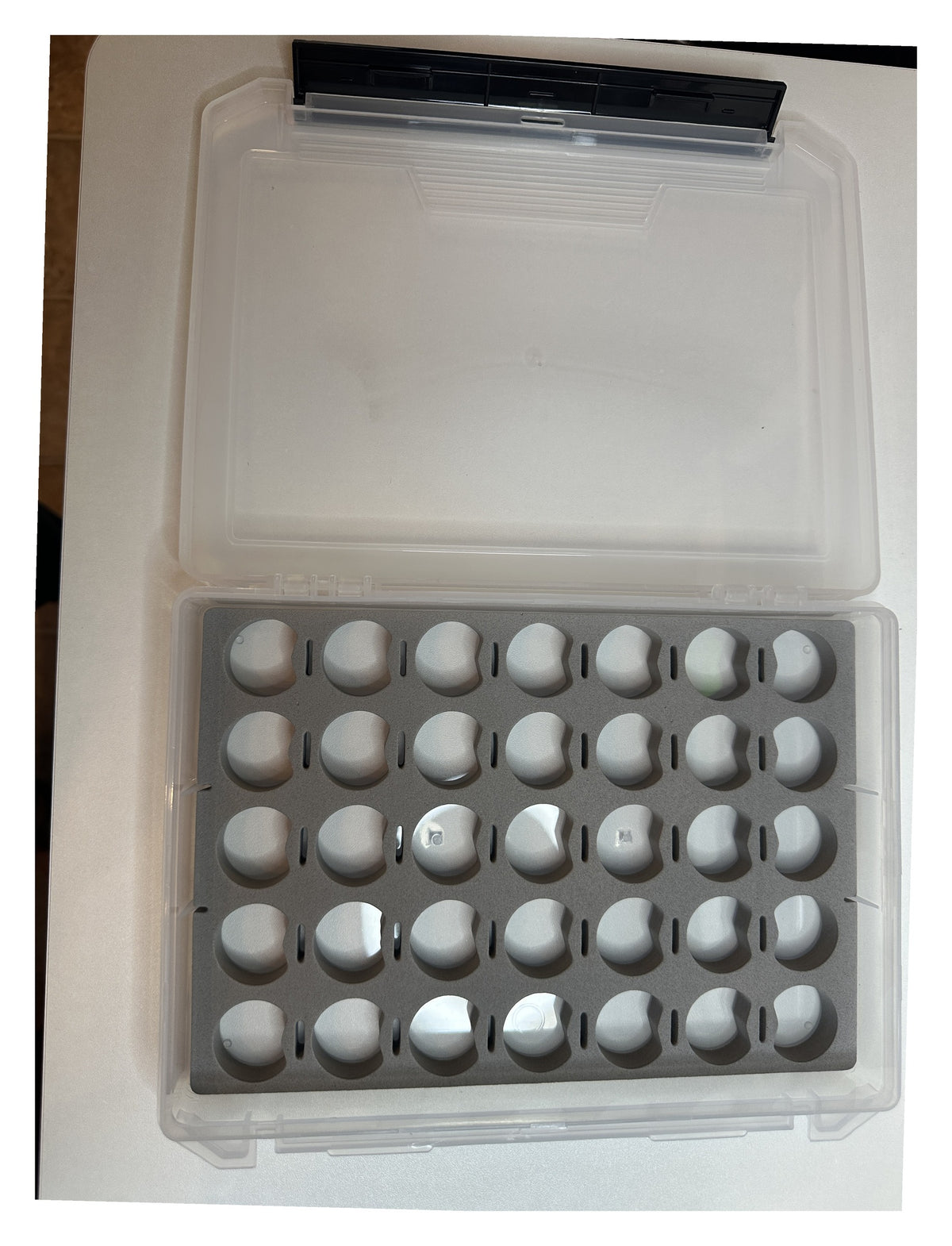 Thread storage box open - clear lid beside the gray foam insert with 35 spool holes